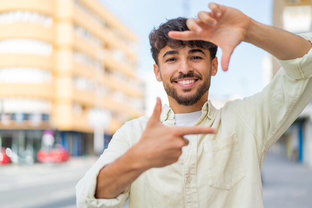 Foto jovem homem bonito árabe ao ar livre focando rosto emoldurando símbolo