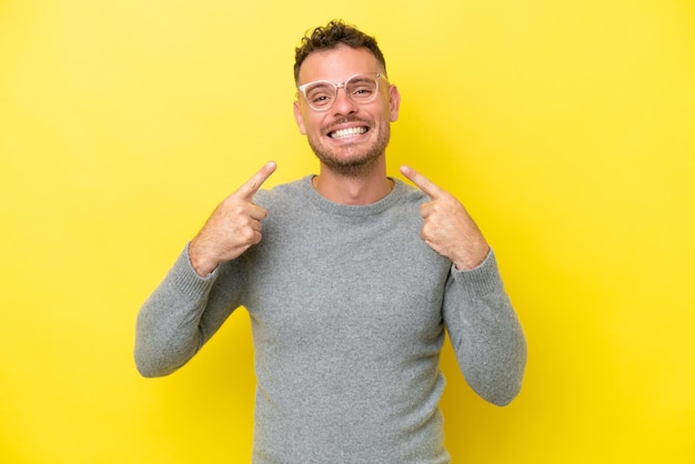 Jovem homem bonito caucasiano isolado em fundo amarelo dando um polegar para cima gesto