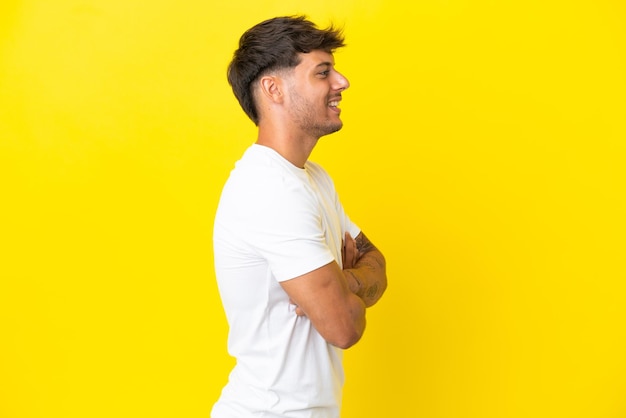 Foto jovem homem bonito caucasiano isolado em fundo amarelo em posição lateral