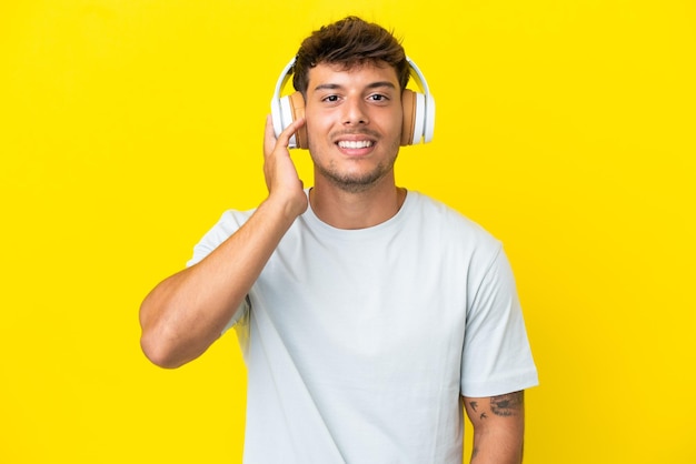 Jovem homem bonito, caucasiano, isolado em um fundo amarelo ouvindo música