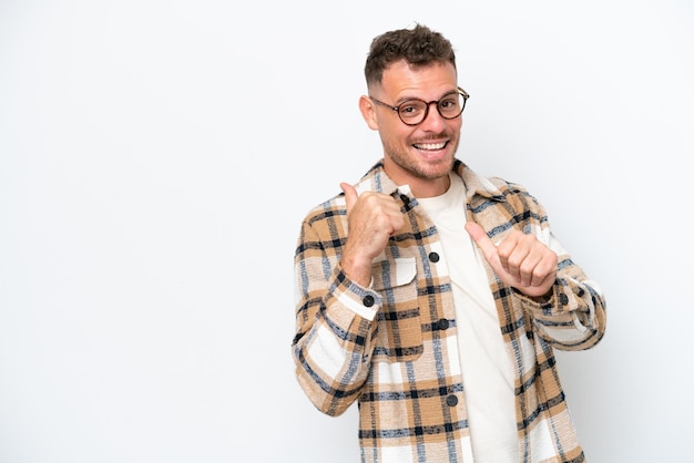 Jovem homem bonito, caucasiano, isolado no fundo branco, apontando para o lado para apresentar um produto