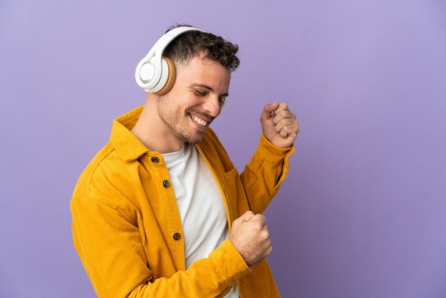 Jovem homem bonito caucasiano isolado ouvindo música e dançando