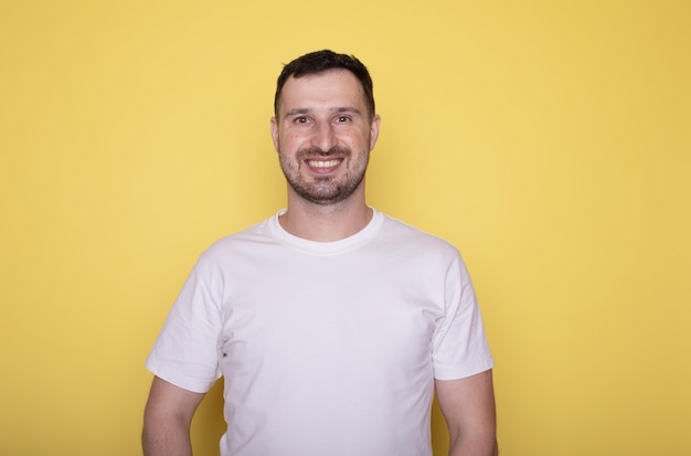 Jovem homem bonito sorridente posando sobre um fundo isolado amarelo