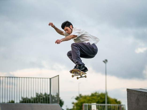 Jovem homem branco fazendo manobras com um skate em uma pista de skate