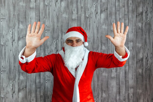 Jovem homem branco vestido de Papai Noel com as mãos para cima