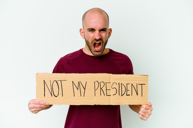 Jovem homem careca caucasiano segurando um cartaz não é meu presidente isolado no fundo branco, gritando com muita raiva e agressividade.