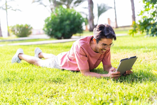 Jovem homem caucasiano ao ar livre em um parque segurando um tablet