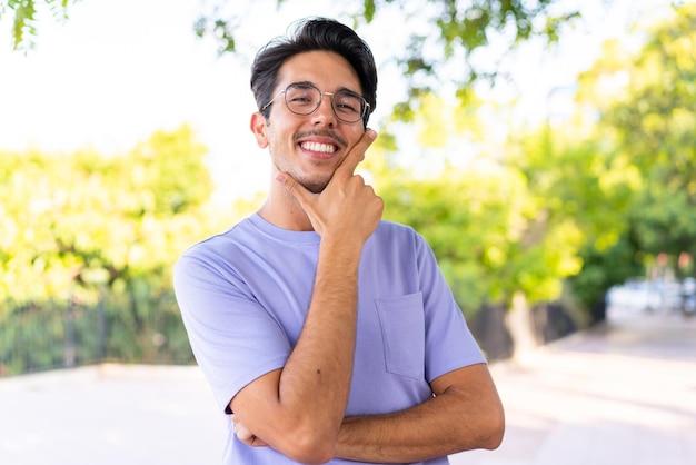 Jovem homem caucasiano ao ar livre em um parque sorrindo