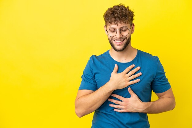 Jovem homem caucasiano bonito isolado em fundo amarelo sorrindo muito