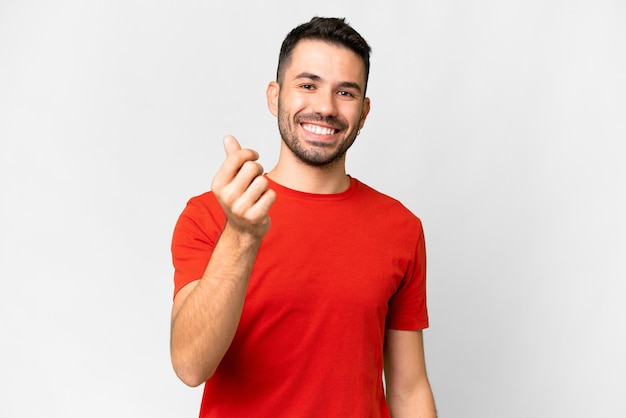 Jovem homem caucasiano bonito sobre fundo branco isolado fazendo gesto de dinheiro