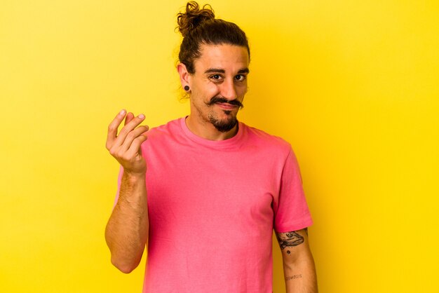 Foto jovem homem caucasiano com cabelo comprido, isolado em um fundo amarelo, mostrando que ela não tem dinheiro.