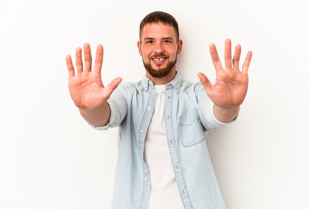 Jovem homem caucasiano com diastema isolado no fundo branco, mostrando o número dez com as mãos.