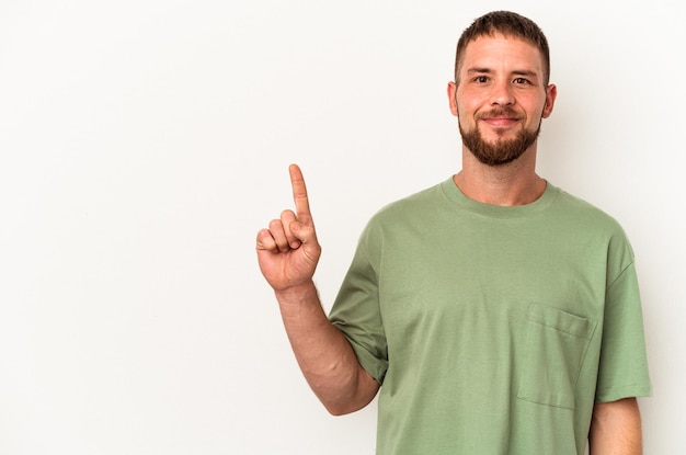 Jovem homem caucasiano com diastema isolado no fundo branco, mostrando o número um com o dedo.