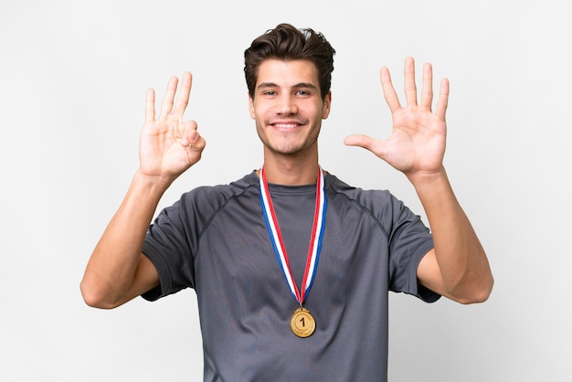 Foto jovem homem caucasiano com medalhas sobre fundo branco isolado, contando oito com os dedos