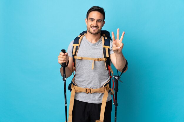 Jovem homem caucasiano com mochila e bastões de trekking