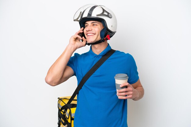 Jovem homem caucasiano com mochila térmica isolada em fundo branco segurando café para levar e um celular