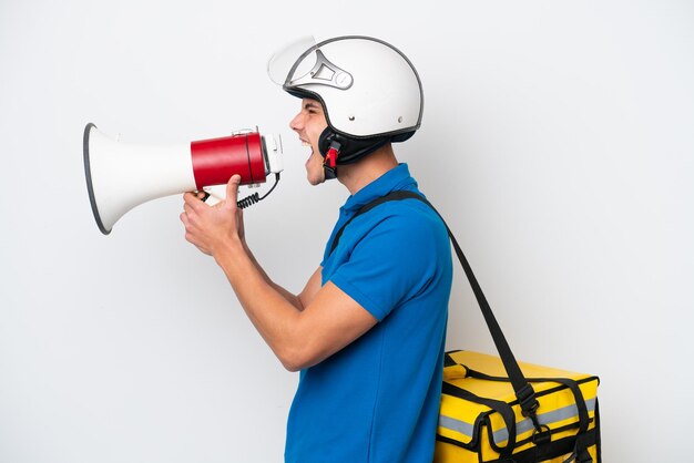 Jovem homem caucasiano com mochila térmica isolada no fundo branco gritando através de um megafone