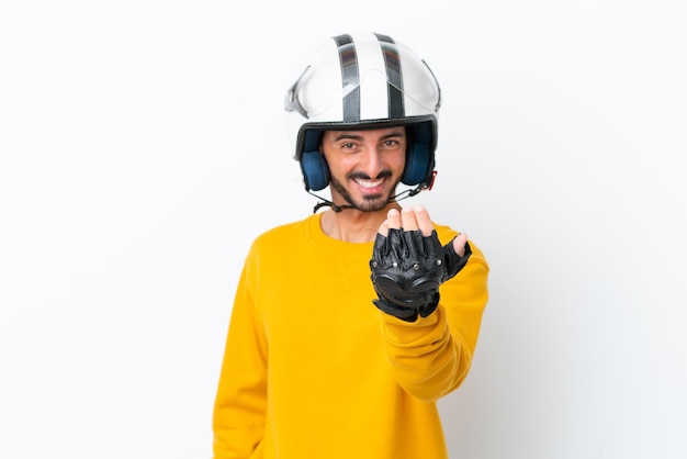 Jovem homem caucasiano com um capacete de moto isolado no fundo branco convidando para vir com a mão feliz por você ter vindo