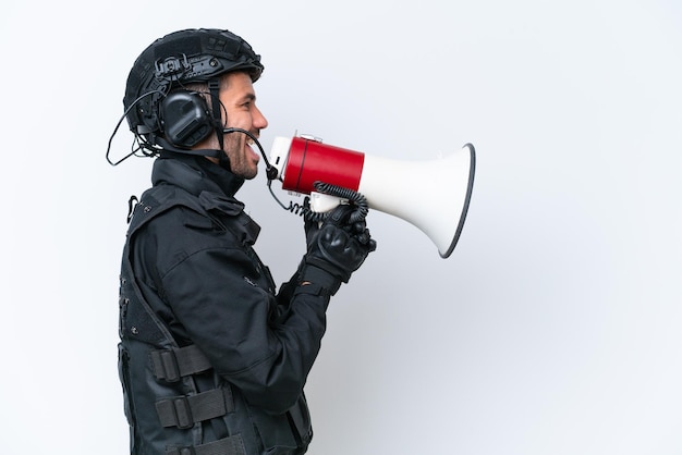 Jovem homem caucasiano da SWAT isolado no fundo branco gritando através de um megafone