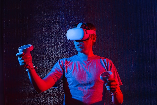 Jovem homem caucasiano de 25-30 anos usando fone de ouvido de realidade virtual e gesticulando enquanto está sentado na luz de néon. VR, futuro, gadgets, conceito de tecnologia.