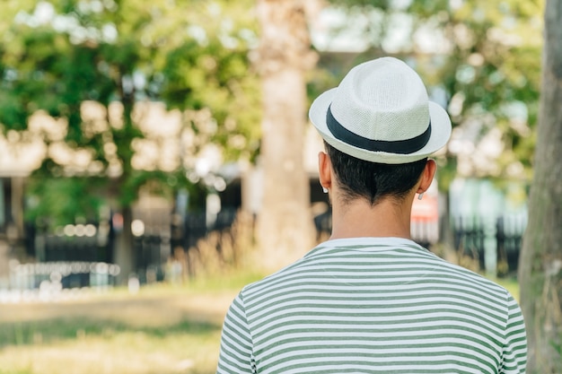 Jovem homem caucasiano de costas ouvindo música em um parque