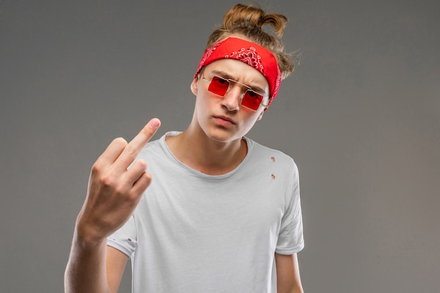 Jovem homem caucasiano em óculos de sol vermelhos, posando de camiseta branca