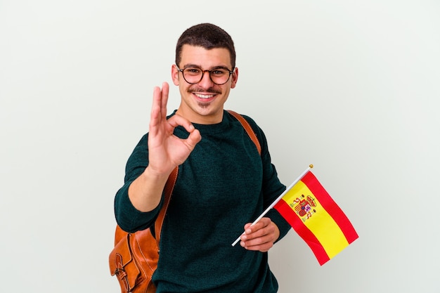 Jovem homem caucasiano estudando inglês isolado no fundo branco, alegre e confiante, mostrando o gesto de ok.