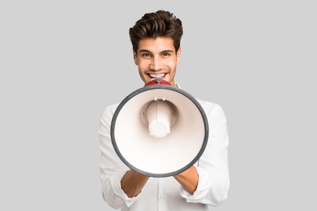 Jovem homem caucasiano gritando com um megafone isolado