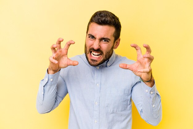 Foto jovem homem caucasiano isolado em fundo amarelo chateado gritando com mãos tensas