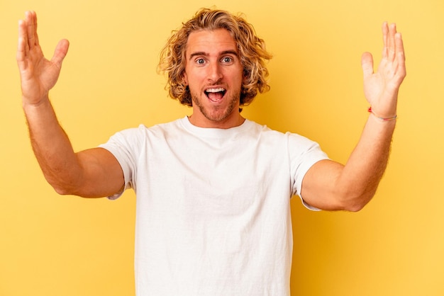 Jovem homem caucasiano isolado em fundo amarelo comemorando uma vitória ou sucesso, ele fica surpreso e chocado.