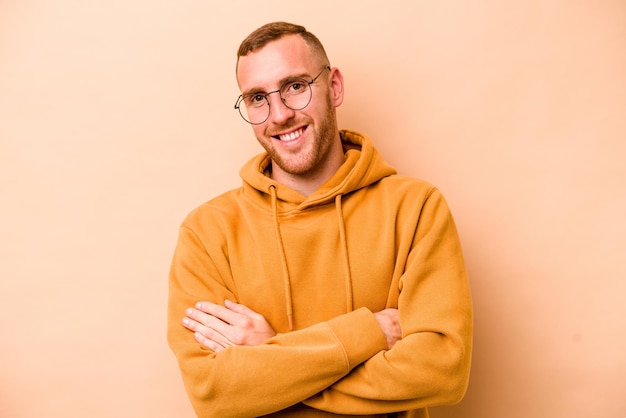 Jovem homem caucasiano isolado em fundo bege feliz sorrindo e alegre