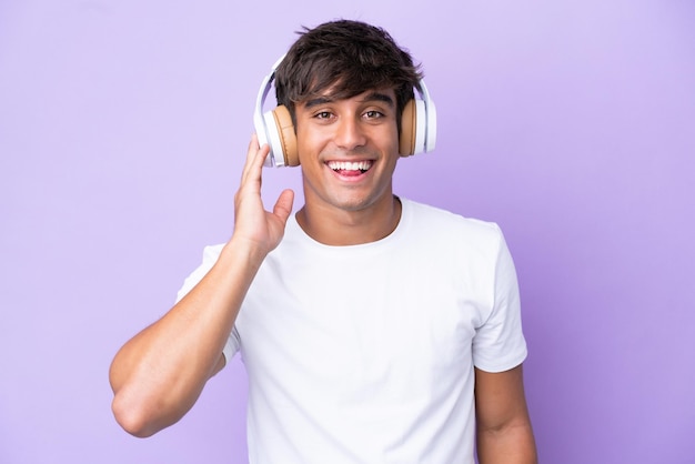 Jovem homem caucasiano isolado em fundo roxo ouvindo música
