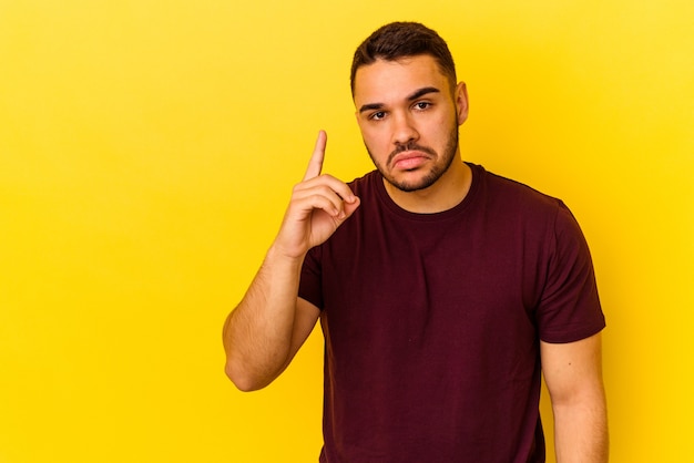 Jovem homem caucasiano isolado em um fundo amarelo, mostrando o número um com o dedo.