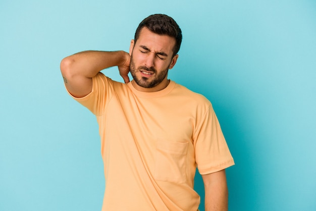 Jovem homem caucasiano isolado em um fundo azul, cansado e com muito sono, mantendo a mão na cabeça.