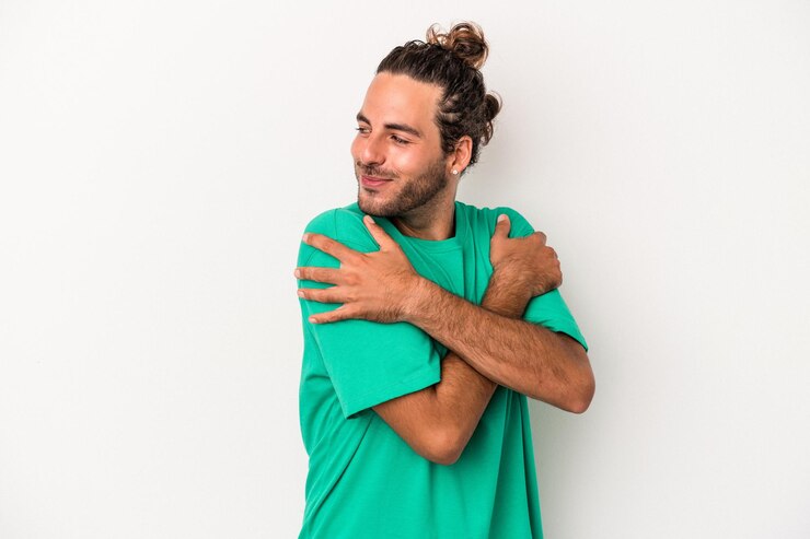 Foto jovem homem caucasiano isolado em um fundo branco abraços, sorrindo despreocupado e feliz.