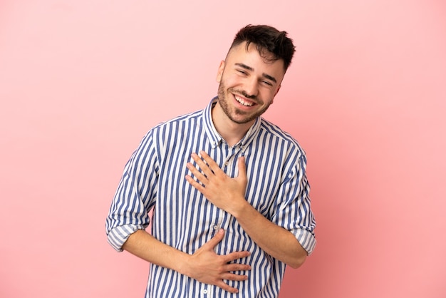 Jovem homem caucasiano isolado em um fundo rosa sorrindo muito