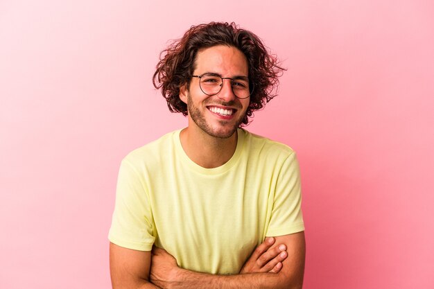 Jovem homem caucasiano isolado na rosa bakcground rindo e se divertindo.