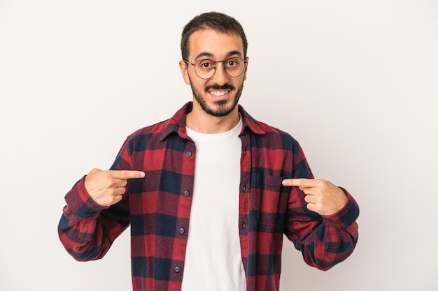 Jovem homem caucasiano isolado no fundo branco aponta para baixo com os dedos, sentimento positivo.