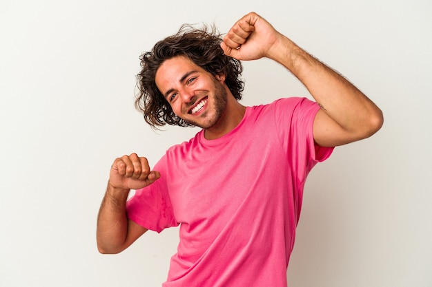 Foto jovem homem caucasiano isolado no fundo branco comemorando um dia especial, pula e levanta os braços com energia.