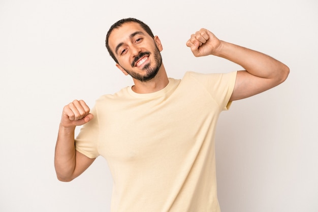 Jovem homem caucasiano isolado no fundo branco comemorando um dia especial, pula e levanta os braços com energia.