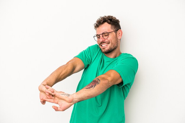 Jovem homem caucasiano isolado no fundo branco, esticando os braços, posição relaxada.