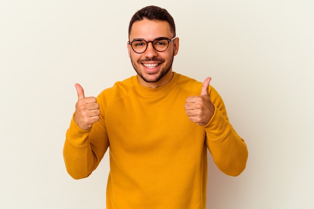 Jovem homem caucasiano isolado no fundo branco, levantando os dois polegares, sorrindo e confiante.