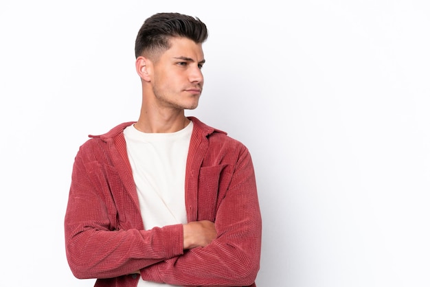 Jovem homem caucasiano isolado no fundo branco, mantendo os braços cruzados