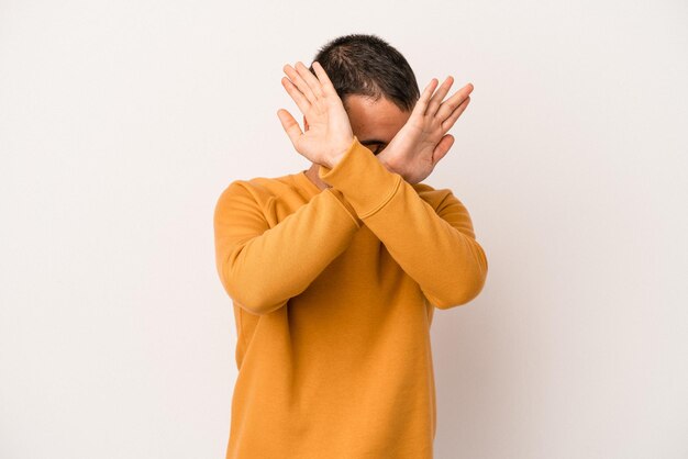 Jovem homem caucasiano isolado no fundo branco, mantendo os dois braços cruzados, conceito de negação.