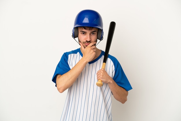 Jovem homem caucasiano jogando beisebol isolado no fundo branco pensando