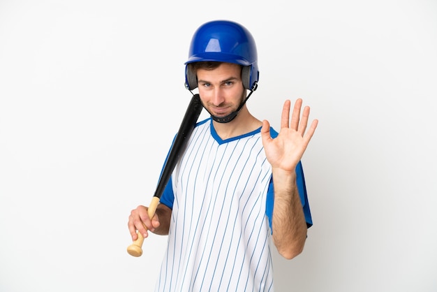 Jovem homem caucasiano jogando beisebol isolado no fundo branco saudando com a mão com expressão feliz