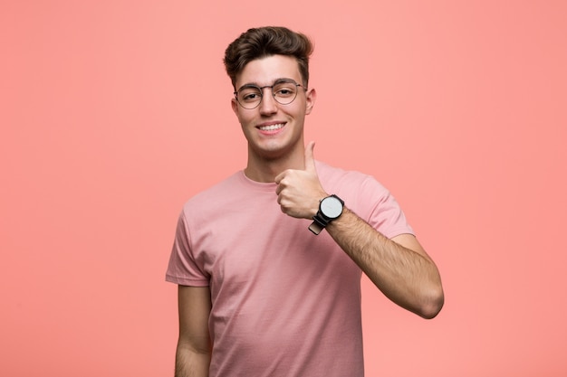 Jovem homem caucasiano legal sorrindo e levantando o polegar