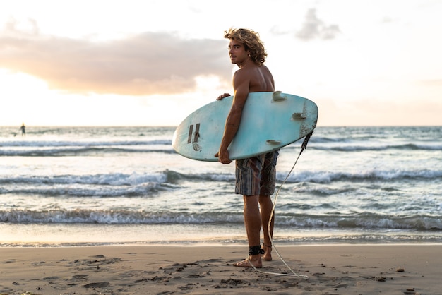 Jovem homem caucasiano levanta cedo para surfar ao nascer do sol
