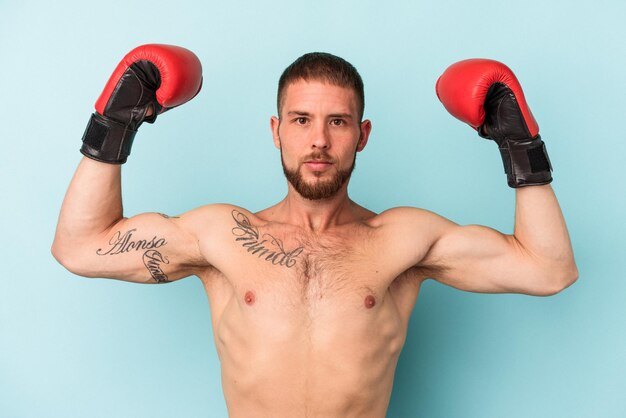 Jovem homem caucasiano praticando boxe isolado em um fundo azul.