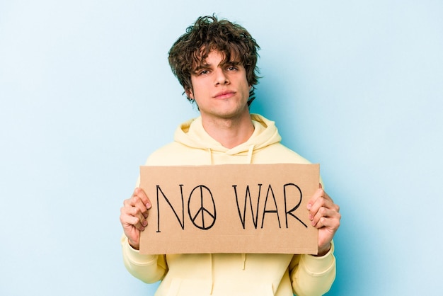 Jovem homem caucasiano segurando nenhum cartaz de guerra isolado em fundo azul